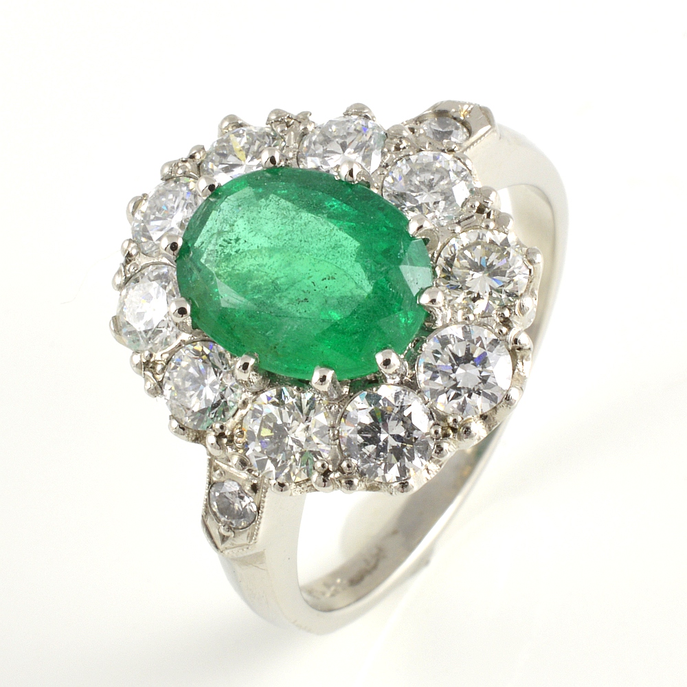 Platinum oval emerald and brilliant cut diamond cluster ring.